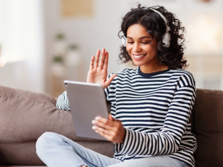 Benefits of a Navii Membership - woman sitting on couch on a video call smiling and waving at camera