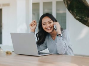 How To Collaborate Using Blogger Outreach To Build SEO - photo of woman sitting at her laptop talking on the phone and smiling