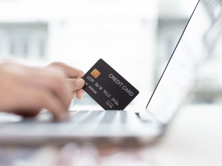 How to increase website conversions - photo of hand holding credit card over laptop