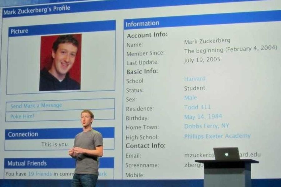 Photo of Facebook founder Mark Zuckerberg standing infront of a large screen which shows his Facebook profile from 2004