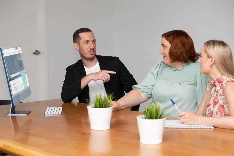 Navii team members sitting in front of a macbook screen discussing the 20% bonus tax deduction for small businesses under the Small Business Skills and Training Boost