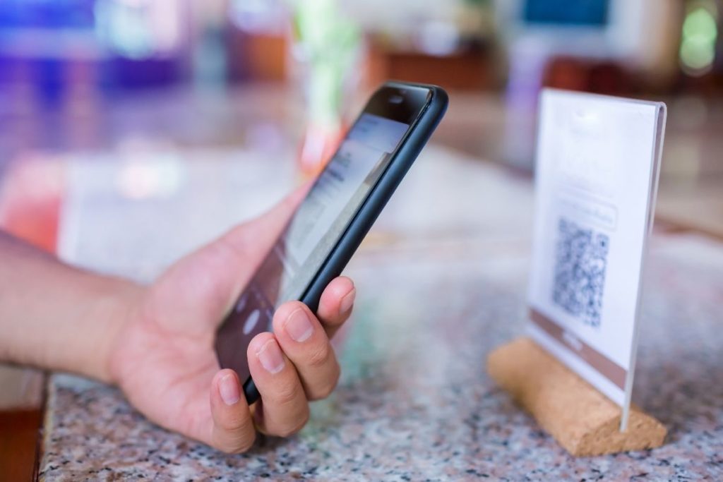 Hand holding phone scans a QR code on display on a counter-top