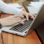 Close up shot of womans hands typing on a laptop