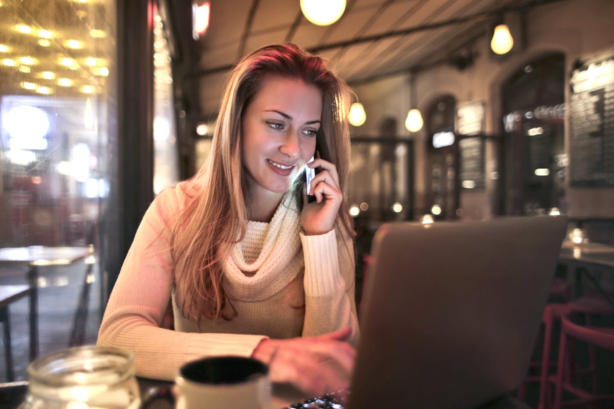 Professional woman on a phone call at a cafe with laptop