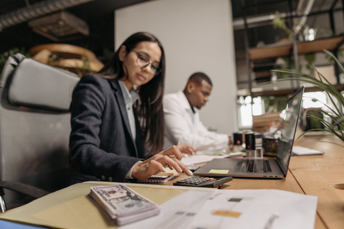 Two business professionals collaborating with a laptop and calculator