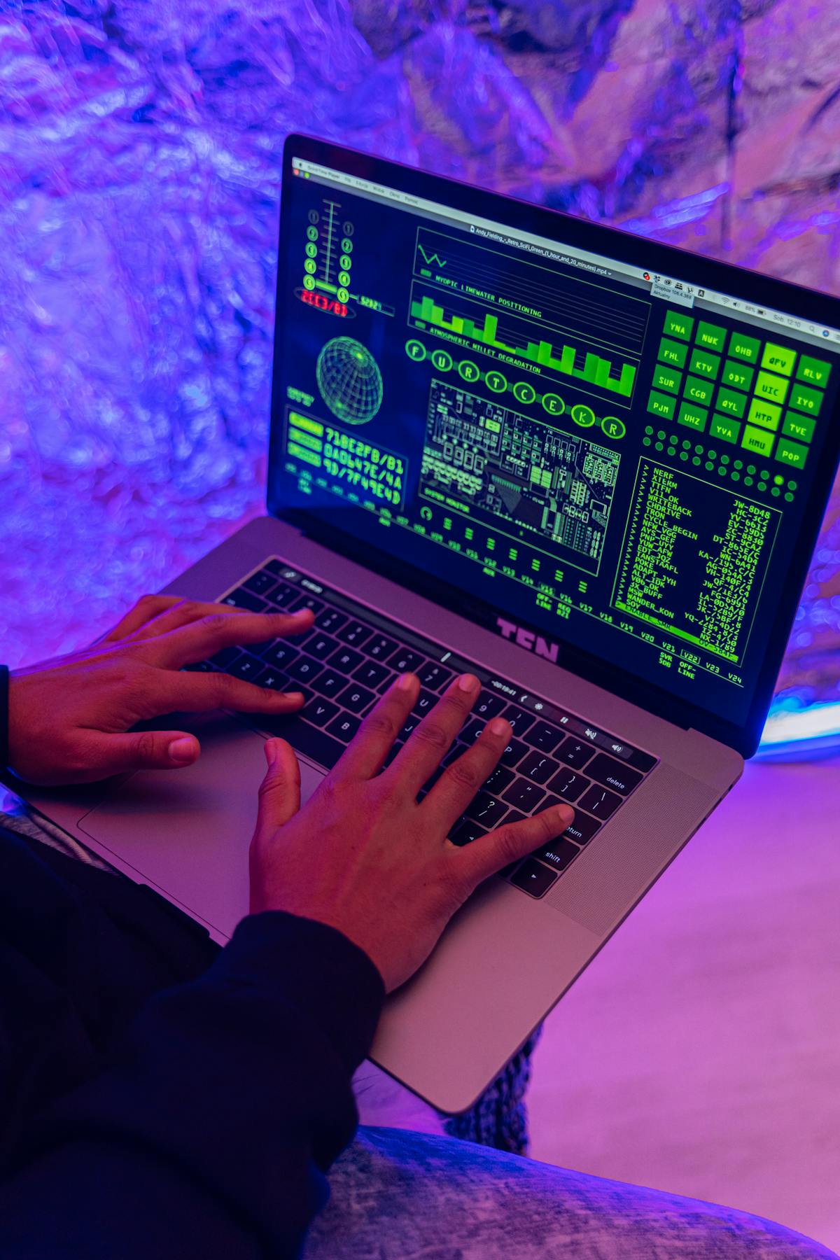 Close-up of hands typing on a laptop displaying security code