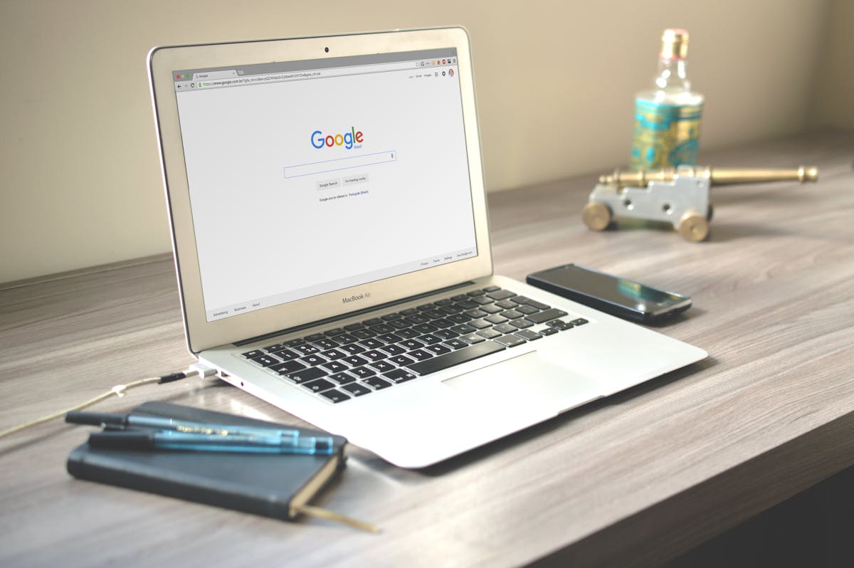 Workspace with laptop showing search engine on wooden desk