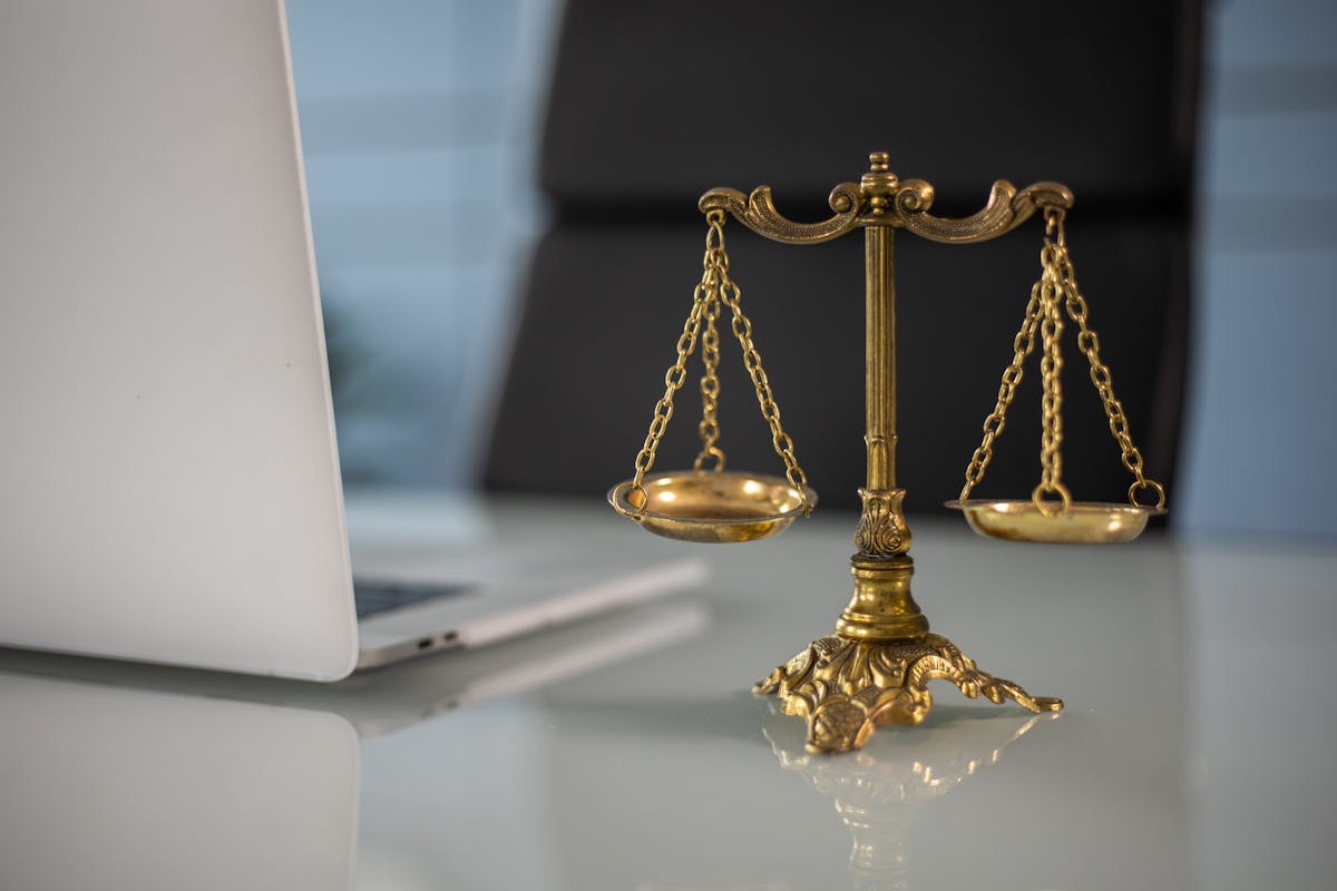 Golden justice scales on a desk beside a laptop