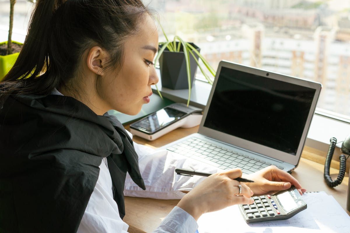 Professional working at a bright desk with laptop and calculator