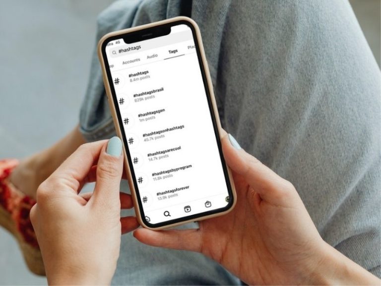 the purpose of instagram hashtags - womans hands holding smart phone searching for hashtags in the instagram app